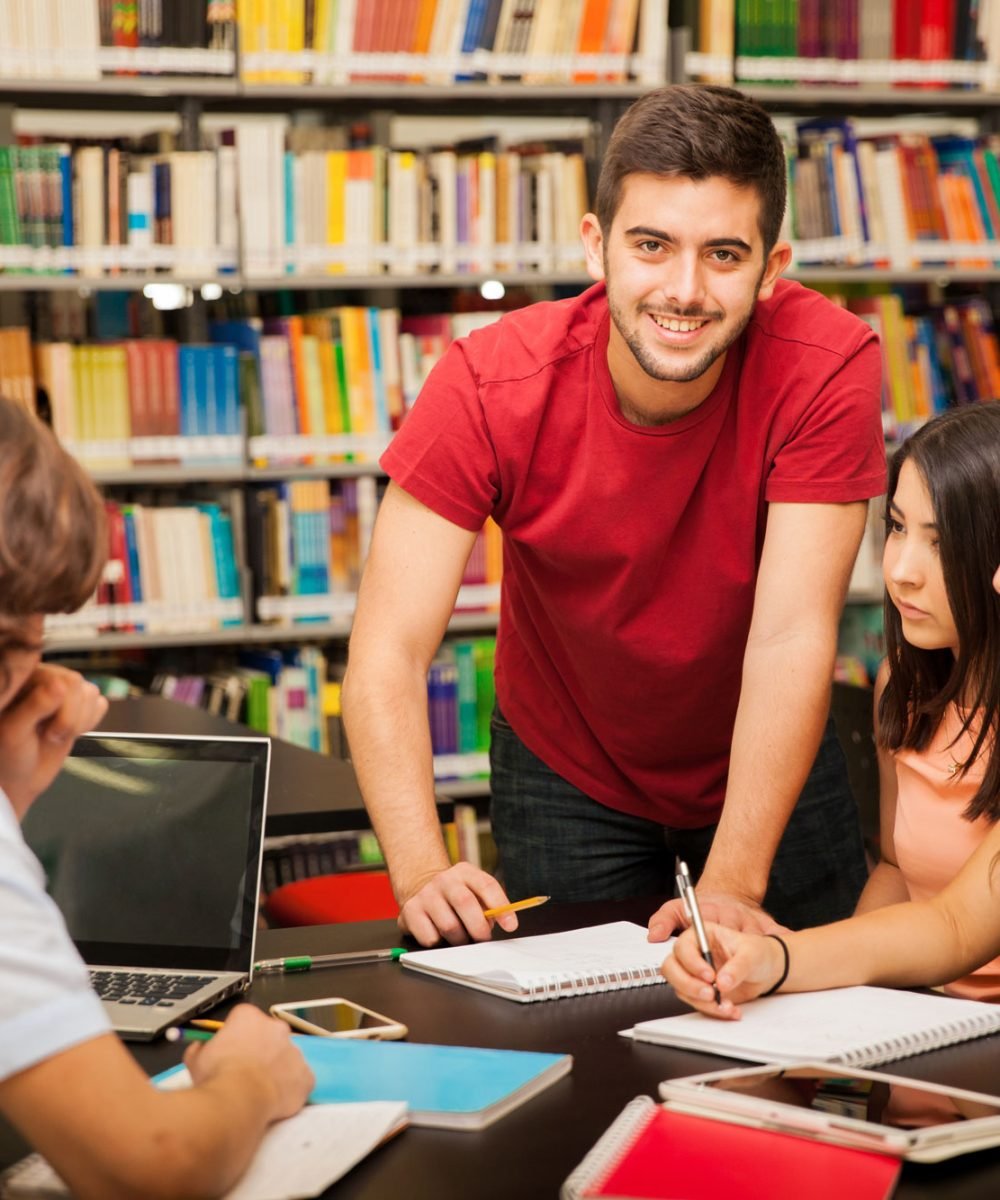 handsome-latin-man-helping-his-colleagues-out-by-explaining-some-his-work-library